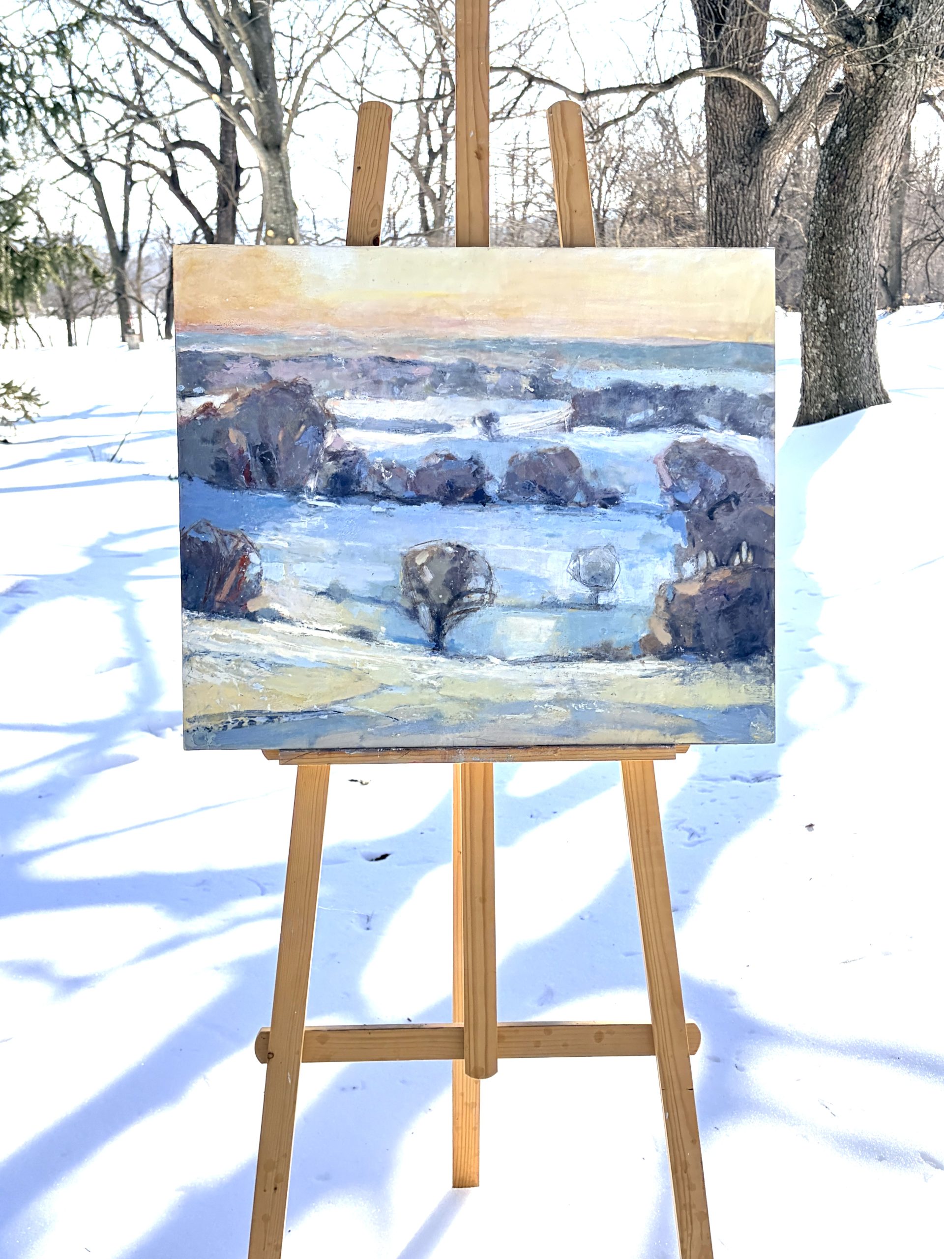 winter snowy landscape painting on an easel outside in the snow